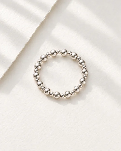 Anillo Dúo de bolas con relieve en plata de ley 925, sobre fondo color crema con sombras suaves