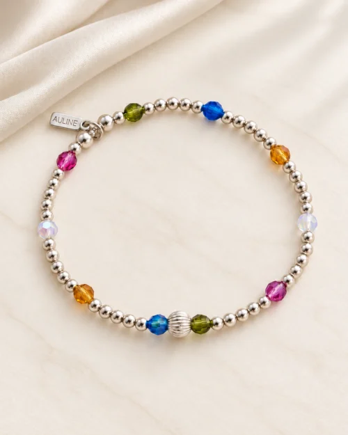Pulsera Pulso de bolas de plata de ley 925 con cristales Preciosa® de colores azul, rosa, verde, ámbar y blanco, sobre fondo color crema con tela satinada