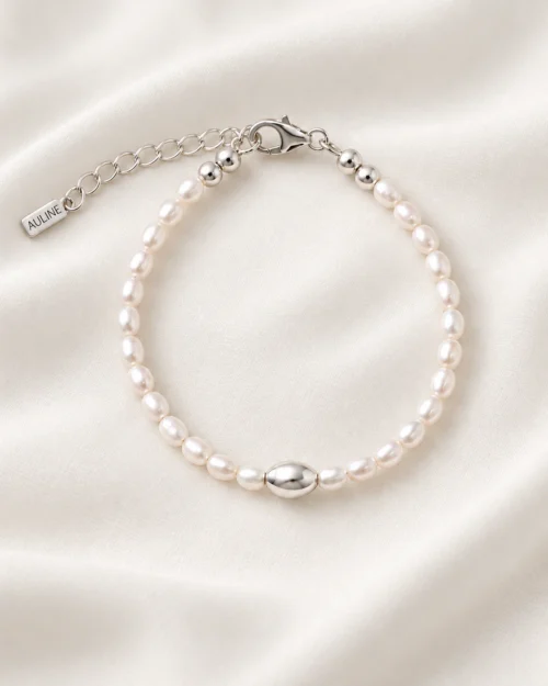Pulsera Alba de perlas naturales barrocas con detalle central ovalado de plata de ley 925, sobre tela satinada color crema